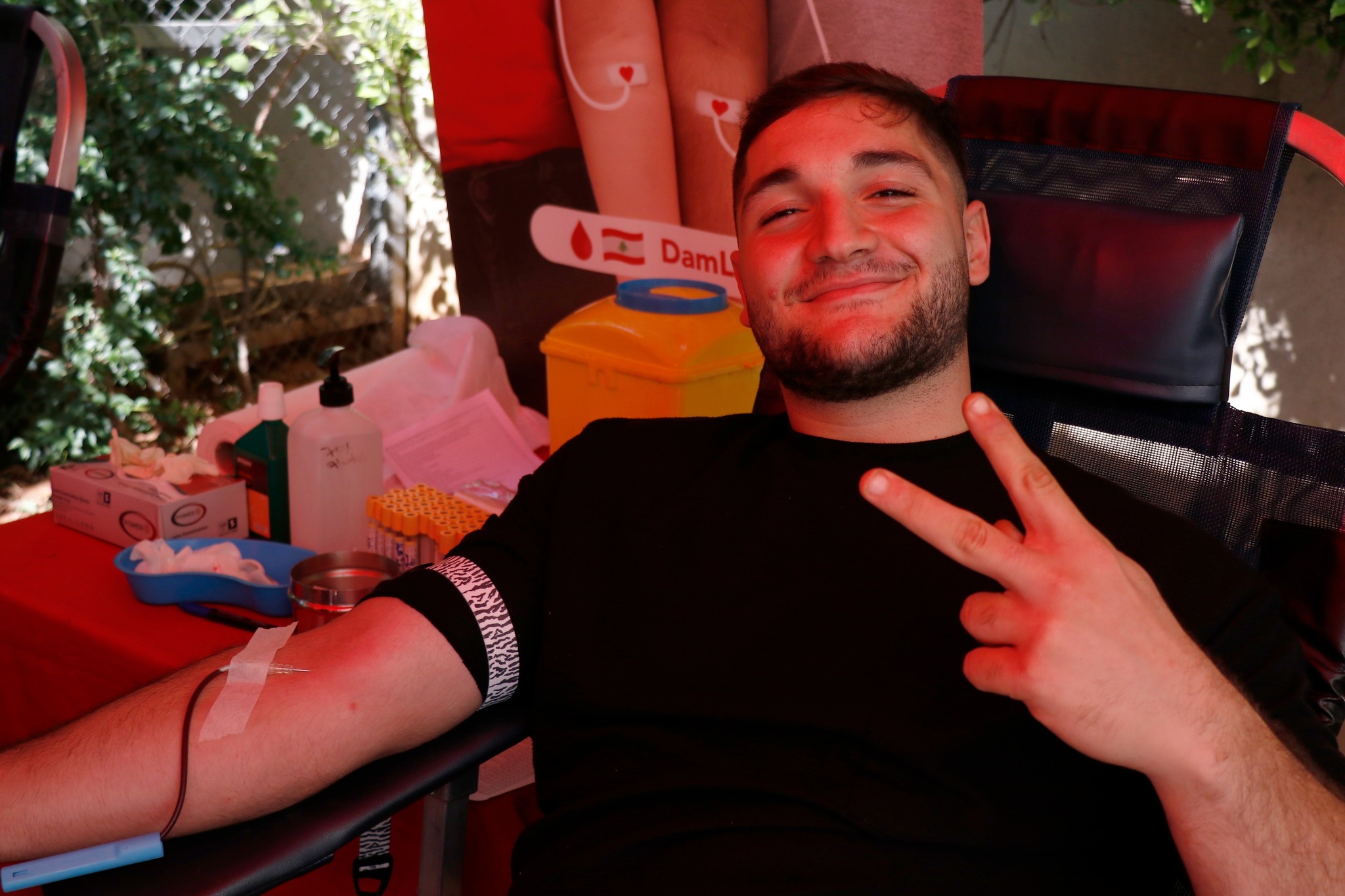 A USAL University student participating in a blood donation event on campus, giving a thumbs-up.