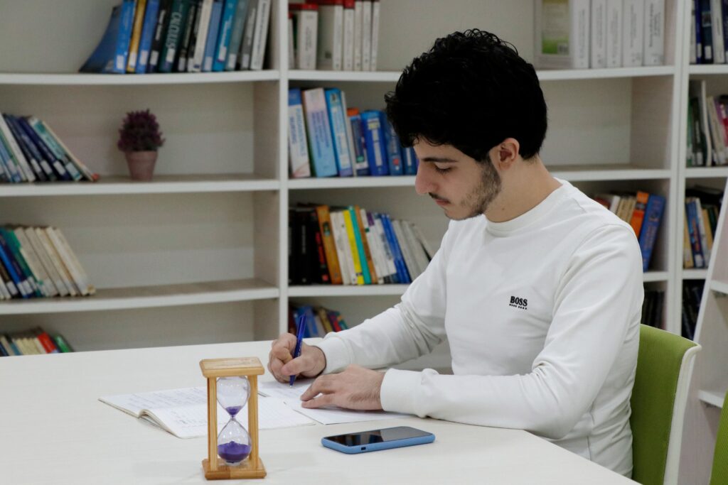 USAL University student studying in the library in Lebanon, surrounded by books and academic resources.