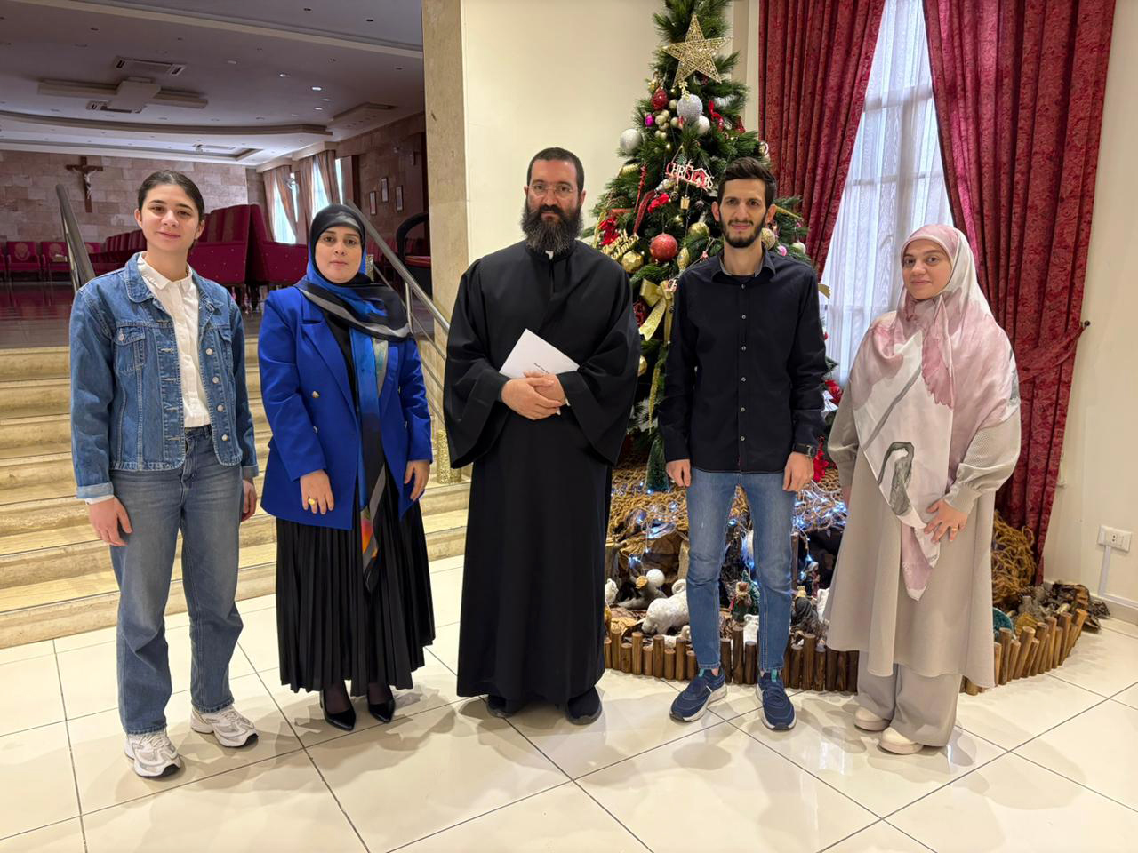 A USAL University delegation posing in front of a Christmas tree during a visit to churches on the occasion of Prophet Jesus’ birth.