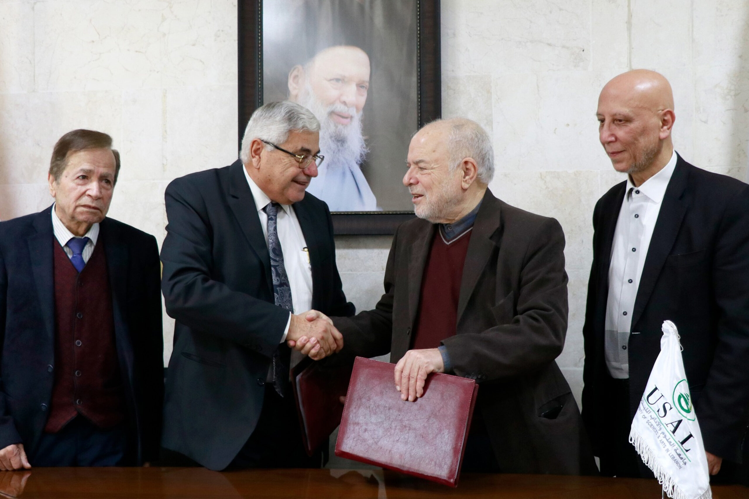 Officials shaking hands during the signing of a community agreement at USAL University, Lebanon.