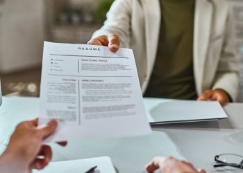 Close-up of job applicant giving his resume during job interview in the office.